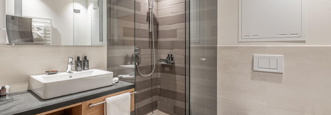 A modern bathroom with a glass shower cabin and a bright sink. The walls are in neutral colors and provide a pleasant atmosphere. - Gletscherblick - Serviced Apartments - Obergurgl 