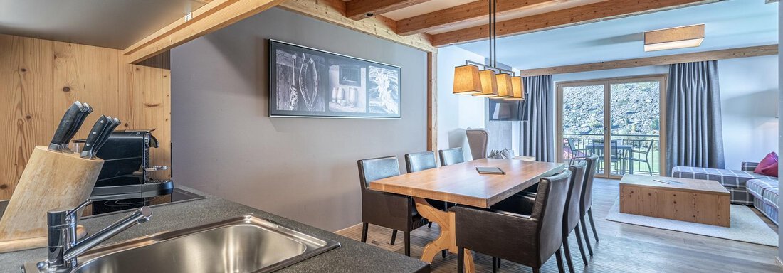 Apt_8_Detail A modern kitchen with a dining area and a cozy living room. The wooden interior gives the space a warm atmosphere. - Gletscherblick - Serviced Apartments - Obergurgl