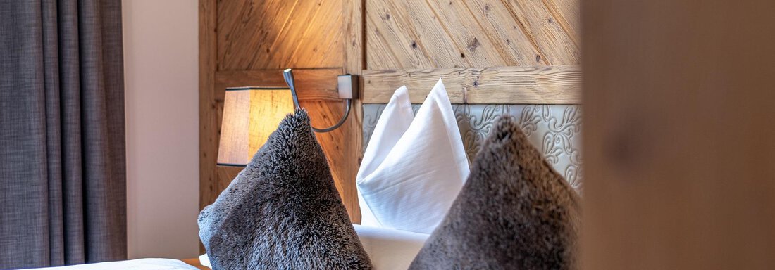 Apt_12_Detail A cozy bedroom with a wooden wall design. Two beds are decorated with soft pillows. - Gletscherblick - Serviced Apartments - Obergurgl