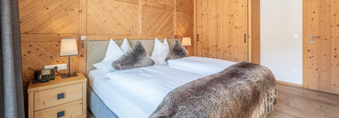 Apt_13_Schlafen A modern bedroom with wood paneling and two beds. There is a cozy atmosphere with elegant decorations and appealing lighting. - Gletscherblick - Serviced Apartments - Obergurgl