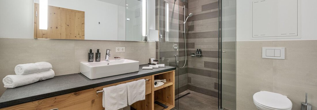 A modern bathroom with a glass shower and an elegant sink unit. The decor is characterized by bright colors and natural materials. - Gletscherblick - Serviced Apartments - Obergurgl 