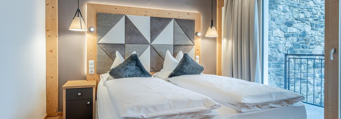 Apt_22_SZ A modern bedroom with a double bed and stylish cushions. Large windows let in plenty of light and offer a view outside. - Gletscherblick - Serviced Apartments - Obergurgl