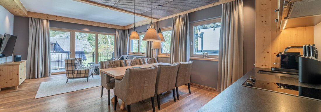 A modern apartment with an open living and dining area. Large windows let in plenty of light and offer a view of the outdoors. - Gletscherblick - Serviced Apartments - Obergurgl 