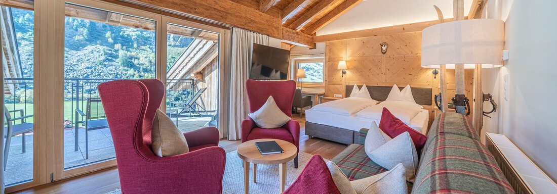 Apt_26_WZ A cozy room with wooden ceilings and modern furniture. Large windows offer a view of the mountains and the balcony. - Gletscherblick - Serviced Apartments - Obergurgl