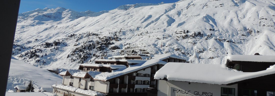 A picturesque winter landscape with snow-covered mountains and several buildings. The clear blue sky enhances the beautiful view. - Haus Christophorus - Obergurgl 