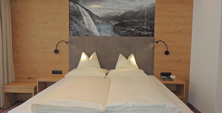 A modern bedroom with a double bed and wooden decor. A picture of a waterfall hangs on the wall. - Haus Christophorus - Obergurgl 