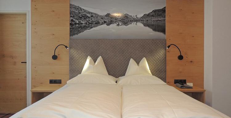 A modern bedroom with a large bed and two pillows. On the wall, there is a picture of a mountain landscape. - Haus Christophorus - Obergurgl 