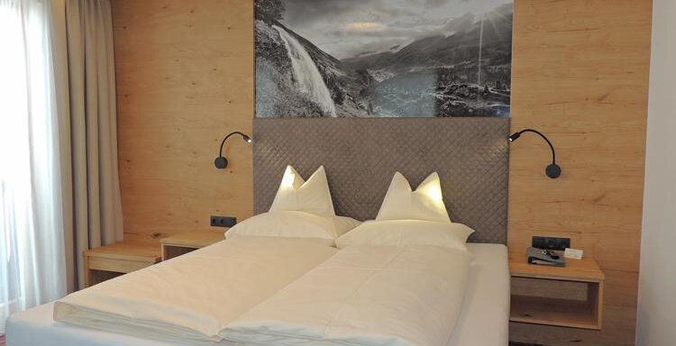 A cozy bedroom with a double bed and bright cushions. An impressive landscape picture is on the wall, and large windows provide plenty of daylight. - Haus Christophorus - Obergurgl 