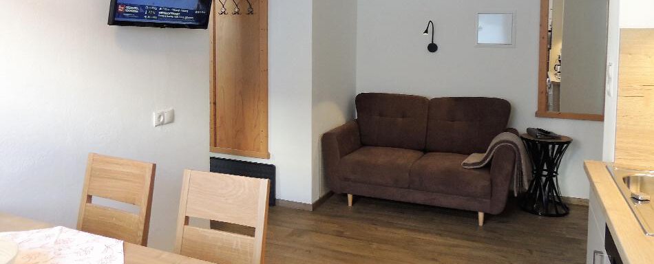 A cozy living area with a sofa and a dining table. A television hangs on the wall and there is a mirror. - Haus Christophorus - Obergurgl 