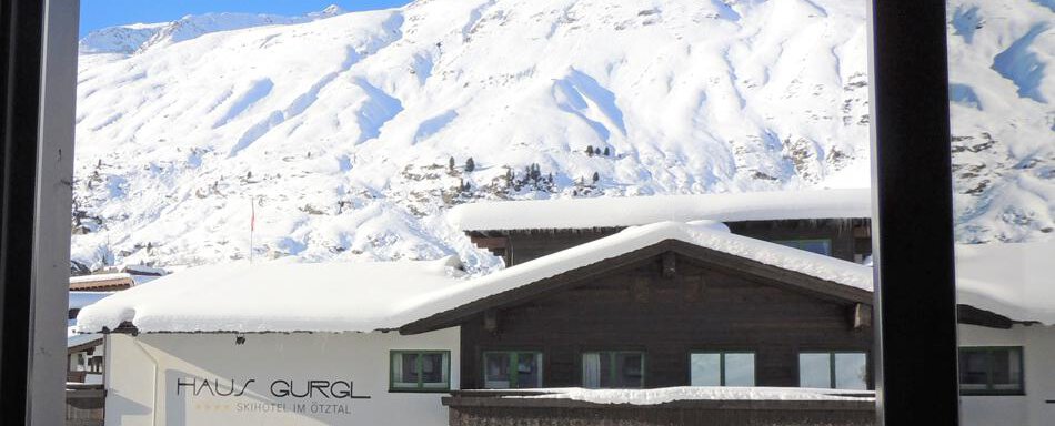 A snowy mountain landscape with a clear blue sky. In the foreground, there is a traditional building with a snow-covered roof. - Haus Christophorus - Obergurgl 