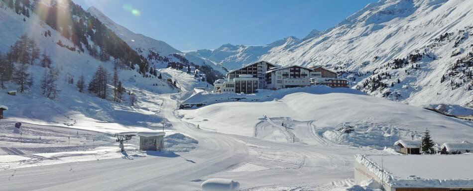 A beautiful winter landscape with snow-covered mountains and a hotel in the distance. The sun shines over the white blanket of snow. - Haus Christophorus - Obergurgl 