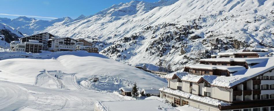 A snow-covered mountain landscape with clear blue sky. In the foreground, modern buildings and huts can be seen. - Haus Christophorus - Obergurgl 
