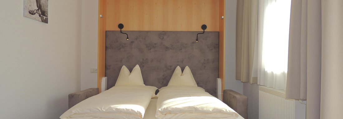 A simple and modern bedroom with a double bed and light sheets.  
Large windows provide plenty of daylight. - Haus Christophorus - Obergurgl 