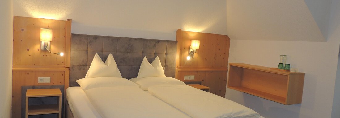 A cozy hotel room with a double bed and wooden paneling. There is a bedside table and a practical wall shelf. - Haus Christophorus - Obergurgl 