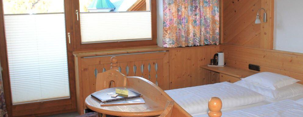 A cozy room with two beds and a small table. Large windows let in plenty of light and offer a beautiful view. - Haus Martinshof - Obergurgl 