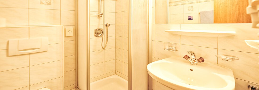 A modern bathroom with a shower, sink, and toilet. The walls are brightly tiled and the lighting is pleasant. - Haus Timmelseck - Obergurgl 