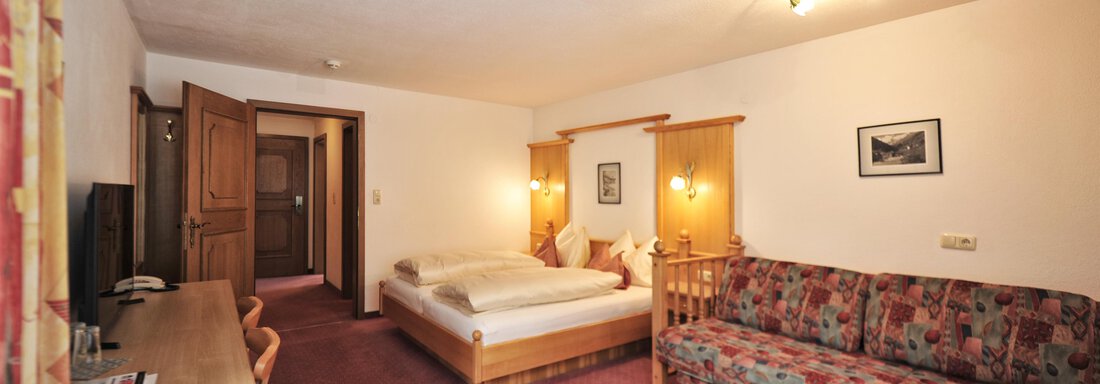 A cozy room with a double bed and a sofa bed. The decor is simple and inviting, with a desk and TV. - Haus Timmelseck - Obergurgl 