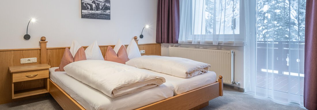 A cozy bedroom with a double bed and two bedside tables. Large windows provide plenty of daylight and a beautiful view. - Haus Timmelseck - Obergurgl 