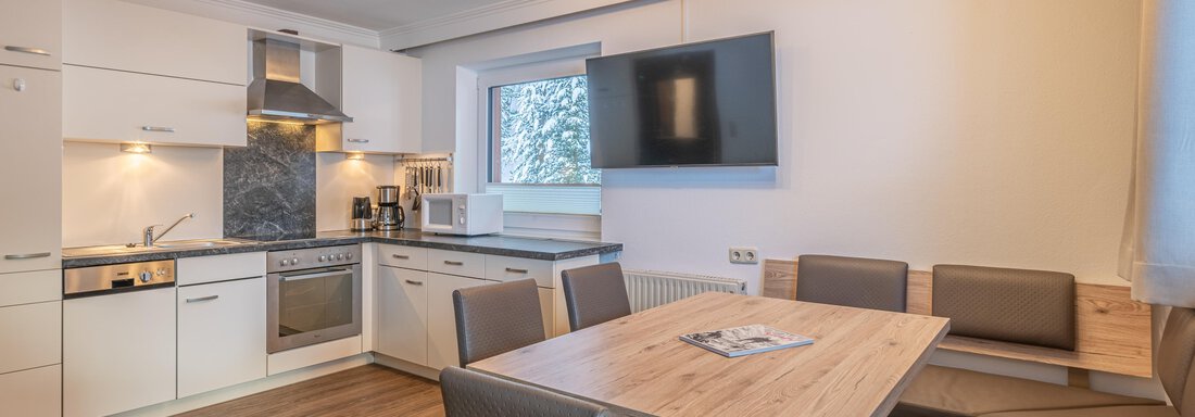 A modern kitchen with a wooden dining area. The room is bright and friendly, equipped with a television and modern appliances. - Haus Timmelseck - Obergurgl 