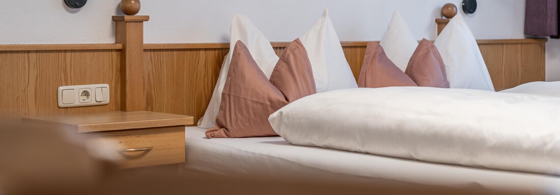 A cozy bedroom with a double bed and decorative cushions. There are modern bedside lamps on the walls. - Haus Timmelseck - Obergurgl 