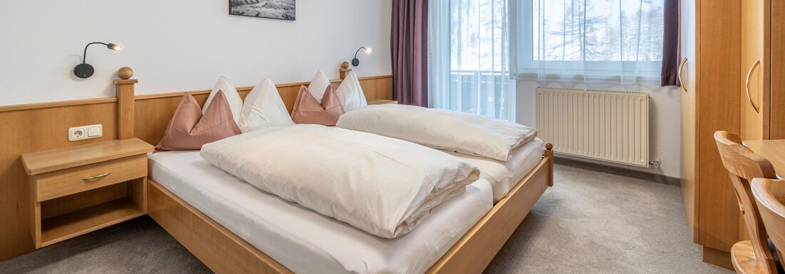 A cozy bedroom with two beds and bright bedding. Large windows provide plenty of daylight and a pleasant atmosphere. - Haus Timmelseck - Obergurgl 
