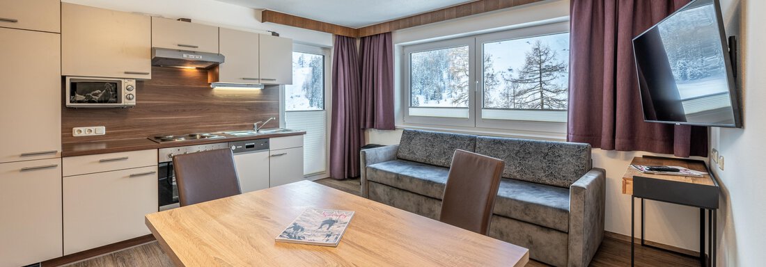A modern kitchen with a dining area and a cozy sofa. Large windows let in plenty of light into the room. - Haus Timmelseck - Obergurgl 