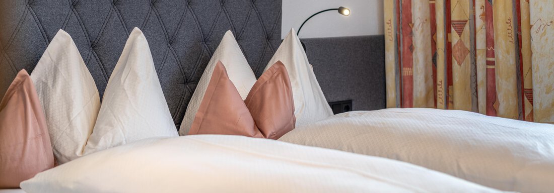 A cozy bedroom with two beds and decorative cushions. The walls are designed with a modern pattern and pleasant lighting. - Haus Timmelseck - Obergurgl 