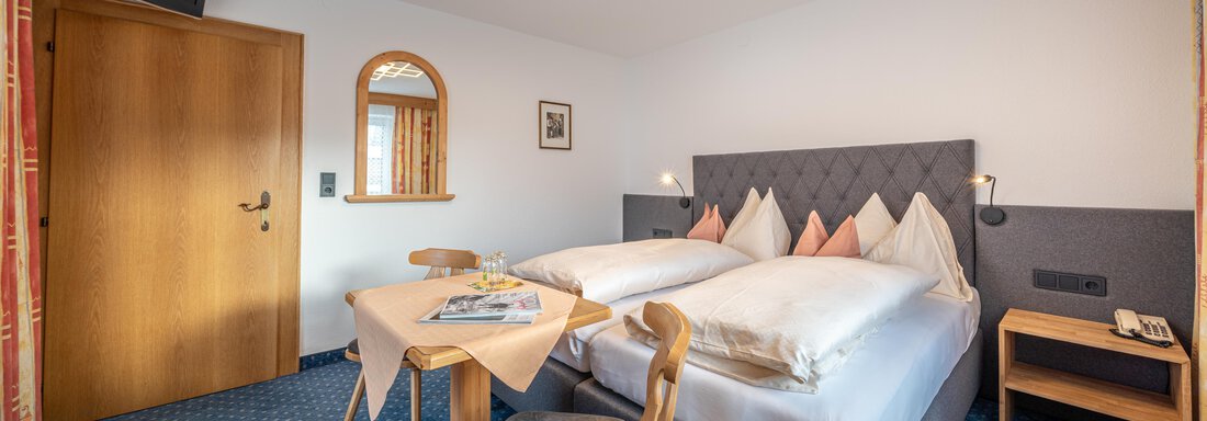 A cozy room with two single beds and modern decorations. A table with chairs and a window with natural light complete the furnishings. - Haus Timmelseck - Obergurgl 