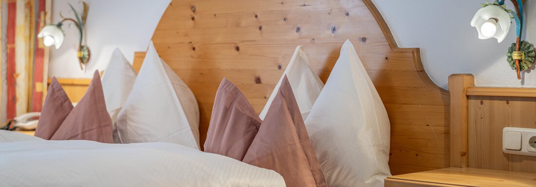 A cozy bedroom with a large bed and elegant pillows. The warm wooden details and soft lighting create a relaxing atmosphere. - Haus Timmelseck - Obergurgl 