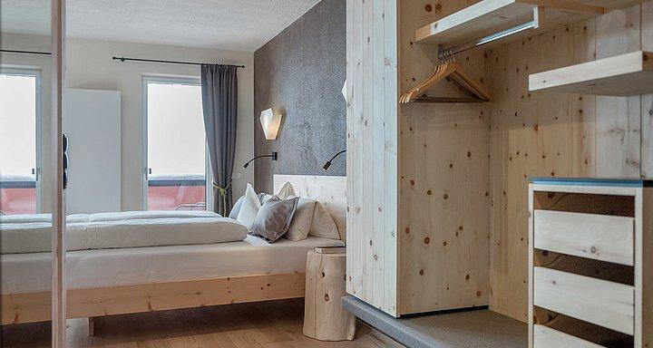 A modern bedroom with light wood and large windows. The room is simply and elegantly furnished. - Hotel-Garni Pirchhütt - Obergurgl 