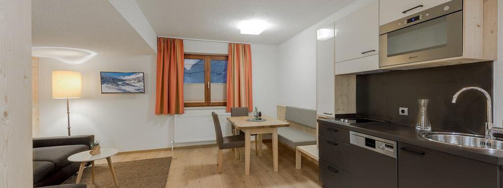Appartement "Rifugio" Wohnraum A modern apartment kitchen with a dining area and a cozy seating corner. Large windows provide plenty of daylight and a welcoming atmosphere. - Hotel-Garni Pirchhütt - Obergurgl