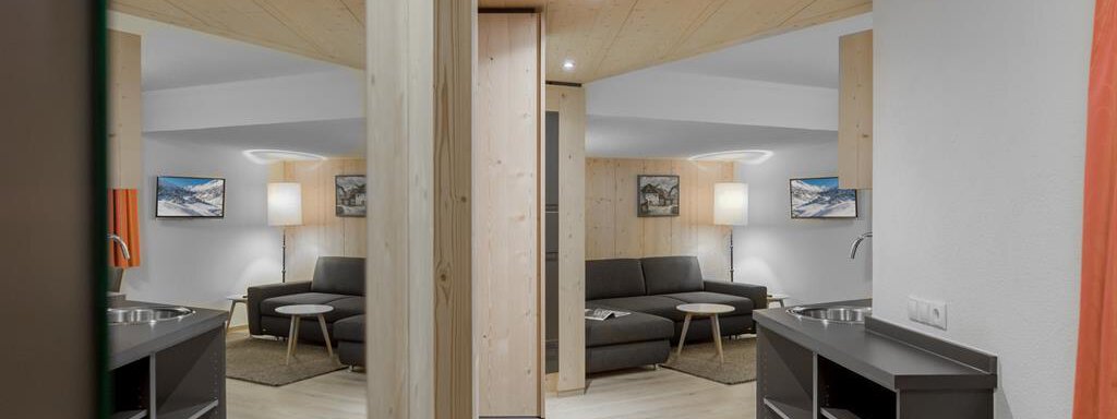 A modern room with a bright wooden ceiling and an open layout. There is a couch, a table, and some cabinets that create a cozy atmosphere. - Hotel-Garni Pirchhütt - Obergurgl 