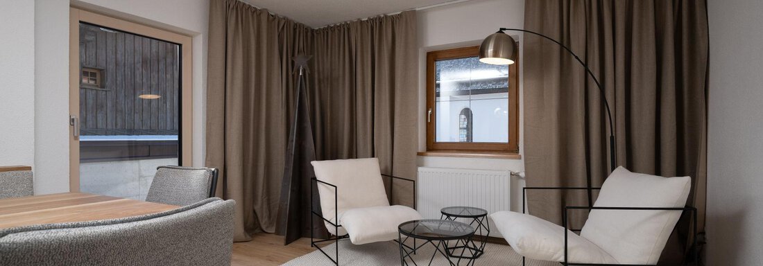Mountain Lodge Lounge A modern furnished living space with two cozy armchairs and an elegant table. Large windows let in plenty of light and create a pleasant atmosphere. - Mountain Lodge Obergurgl - Obergurgl