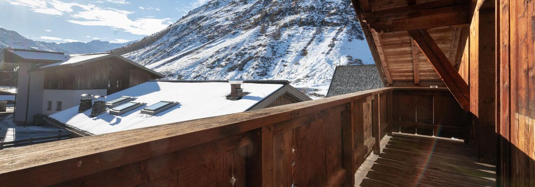 A balcony with wooden cladding and a view of snow-capped mountains. The sun is shining brightly in the sky. - Mountain Lodge Obergurgl - Obergurgl 