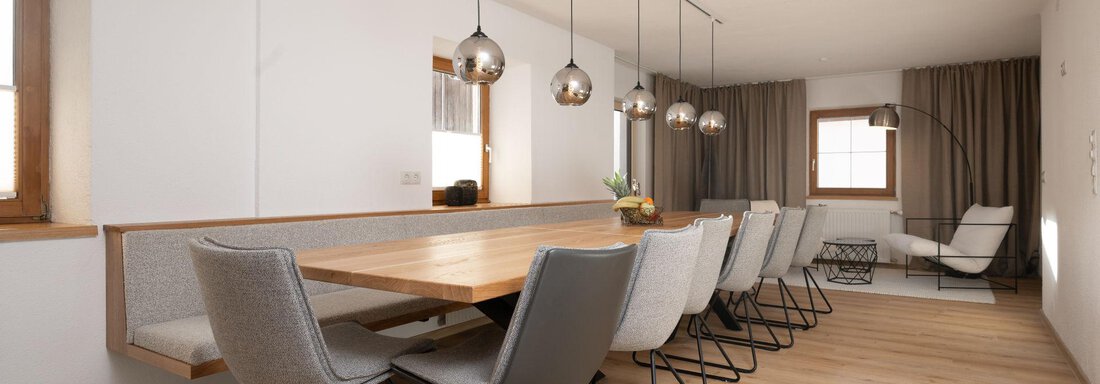 A modern dining room with a long wooden table and stylish chairs. Large windows and subtle lighting create a bright, inviting atmosphere. - Mountain Lodge Obergurgl - Obergurgl 
