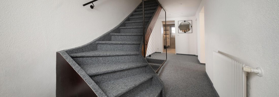 An elegant staircase with gray carpet and a modern railing. The hallway is bright and tidy. - Mountain Lodge Obergurgl - Obergurgl 