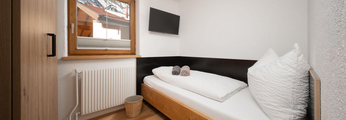A small, modern bedroom with a single bed and a window. The wooden ceiling and floor give the room a pleasant atmosphere. - Mountain Lodge Obergurgl - Obergurgl 