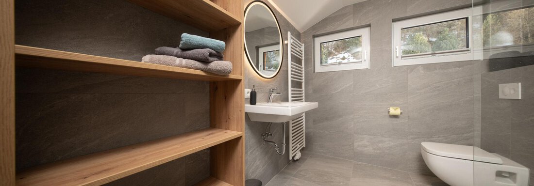 A modern bathroom with wooden shelves, a large mirror area, and bright, neutral colors. The space feels clean and inviting. - Mountain Lodge Obergurgl - Obergurgl 