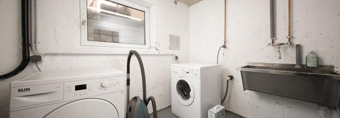 A modern laundry room environment with a washing machine, a dryer, and a sink. Bright walls and a window provide plenty of light. - Mountain Lodge Obergurgl - Obergurgl 