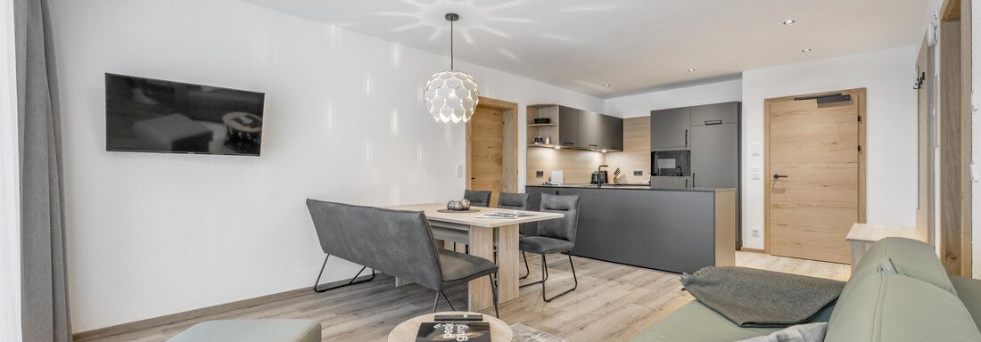 A modern living kitchen with a cozy sofa and dining table. Bright colors and stylish furniture create an inviting atmosphere. - Peak Gurgl - Obergurgl 