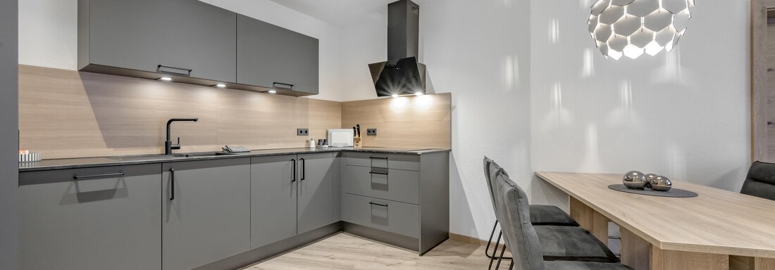 Peak Gurgl Top 2 | © Peak Gurgl (CC C) A modern kitchen with gray cabinets and wood details. A bright dining area with a table and chairs complements the cozy atmosphere. - Peak Gurgl - Obergurgl