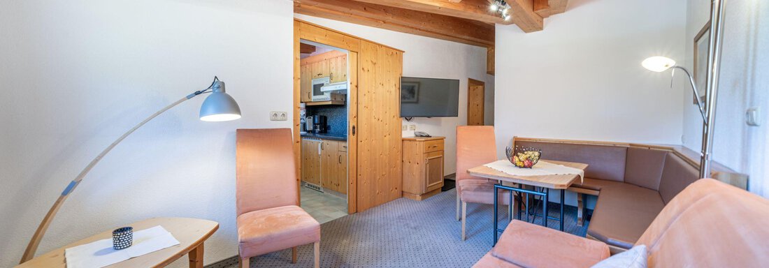 A cozy living room with a wooden beam ceiling, a sofa, and a dining area. The room is bright and furnished in a modern style. - Schönblick Gurgl - Obergurgl 