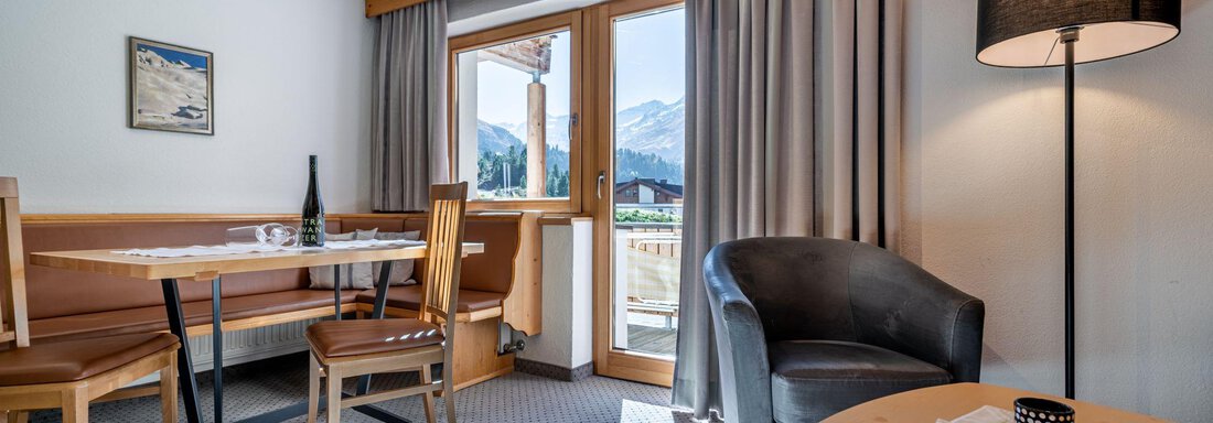 Wohnraum Appartement 2 A cozy living area with a table and chairs. The large window front lets in plenty of daylight and offers a view outside. - Schönblick Gurgl - Obergurgl