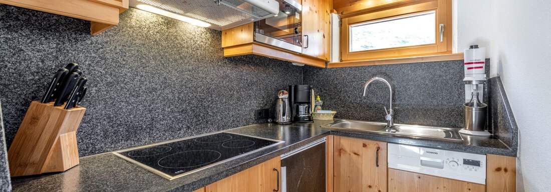 A modern kitchen with wooden cabinets and granite surfaces. It is well equipped with cooking appliances and accessories. - Schönblick Gurgl - Obergurgl 