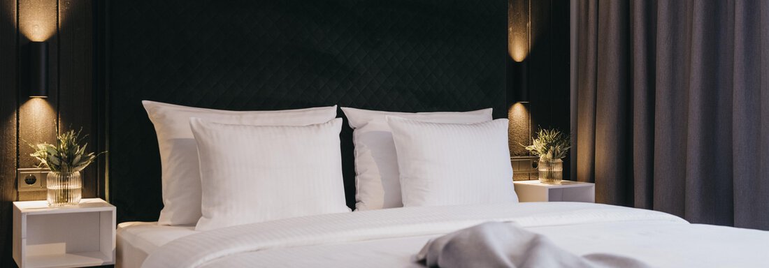 A modern bedroom with a large double bed and soft pillows. Gentle lighting and curtains create a cozy atmosphere. - The Crystal VAYA Unique - Obergurgl 