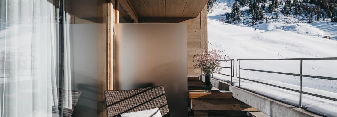 A cozy balcony with modern furniture and a view of snow-covered mountains. The warm wooden paneling creates an inviting atmosphere. - The Crystal VAYA Unique - Obergurgl 