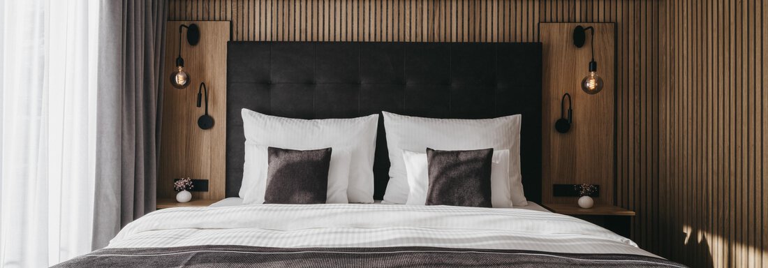 A modern bedroom with a large, comfortable bed and bright curtains. The walls are decorated with warm wooden elements. - The Crystal VAYA Unique - Obergurgl 
