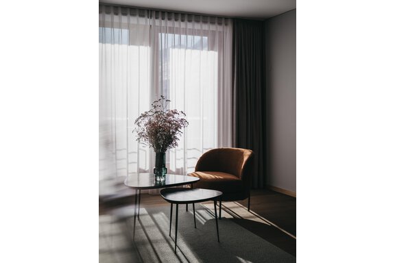 An elegant room with a cozy armchair and a small table. A bouquet in a vase adds a touch of color. - The Crystal VAYA Unique - Obergurgl 