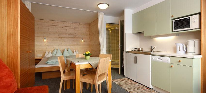 Wohnraum A cozy apartment with a dining area and a small kitchen. The room is bright and friendly furnished, ideal for a relaxing stay. - Ferienwohnungen Broser - Obergurgl