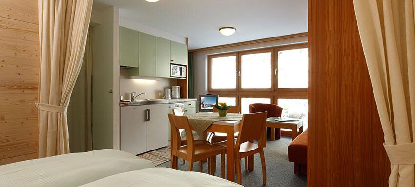 A modern apartment with an open living area and kitchen. Large windows provide plenty of natural light. - Ferienwohnungen Broser - Obergurgl 